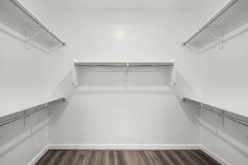 an empty walk in closet with white walls and a wood floor